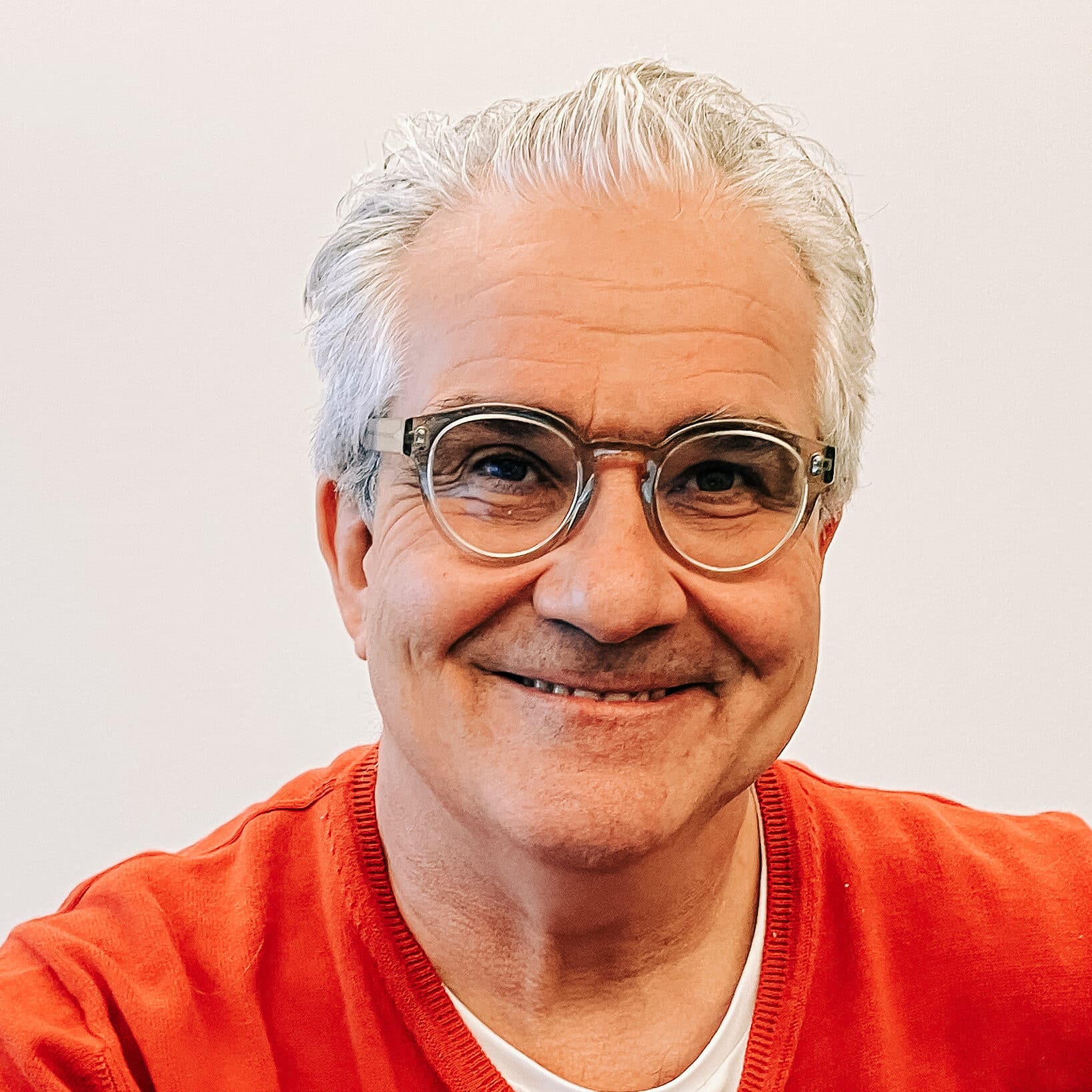 Lorenz Steinmann trägt einen roten Pullover und darunter ein weisses T-Shirt. Er trägt eine Brille.