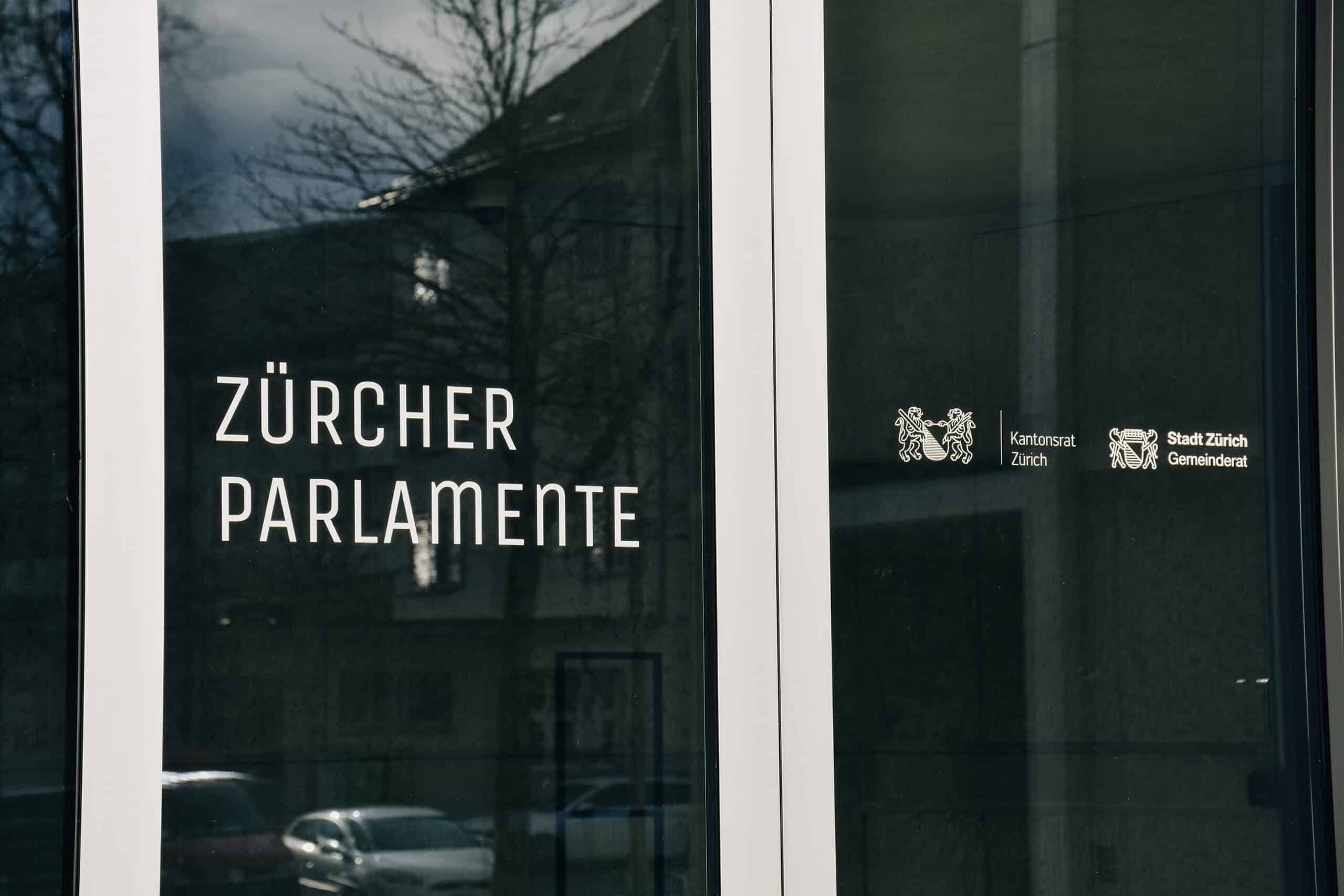 Die Glastüren des Eingangs des Rathaus Hard mit der Beschriftung "Zürcher Parlamente".