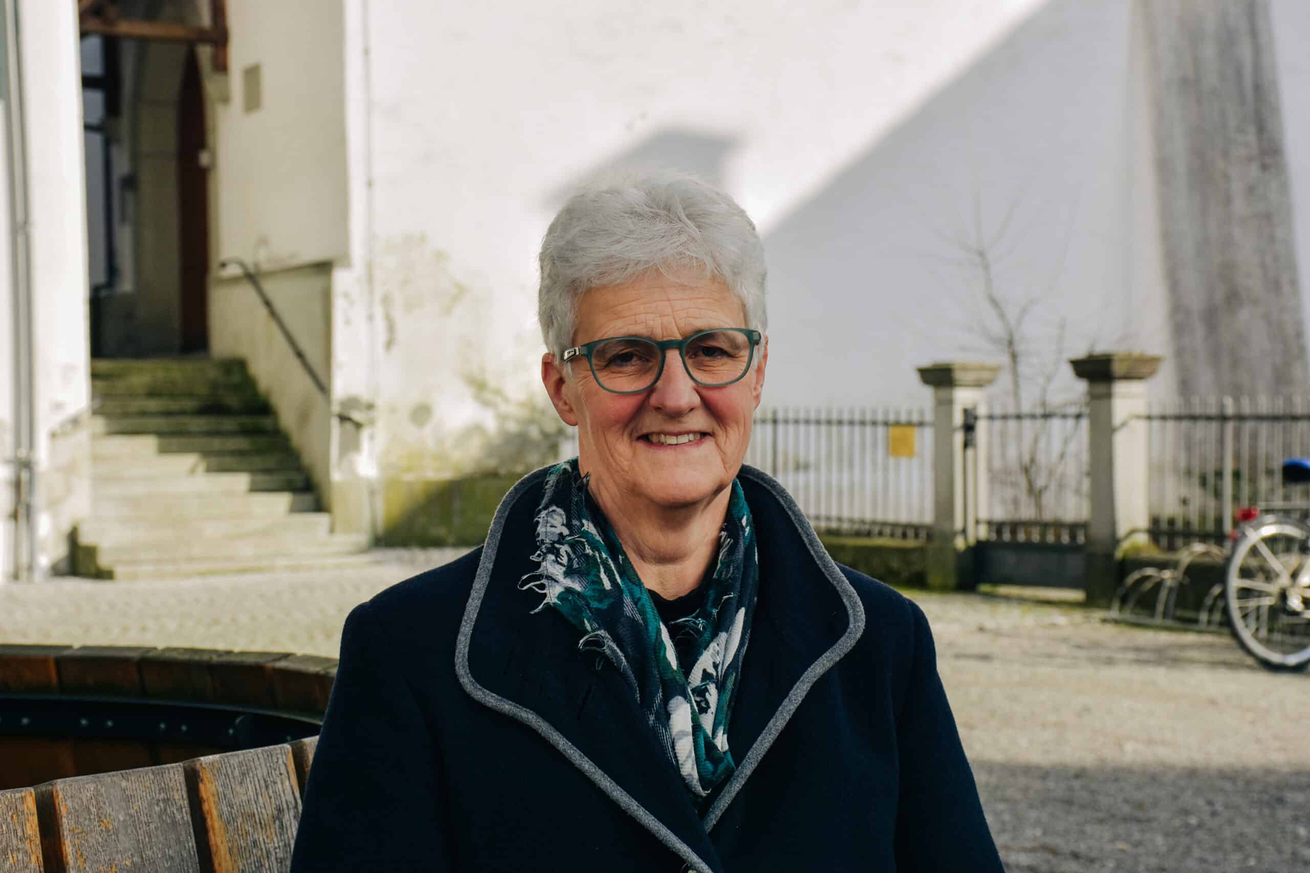 Ruth Büchi-Vögeli sitzt auf einer Bank. Im Hintergrund ist die Altstadt von Elgg zu sehen.