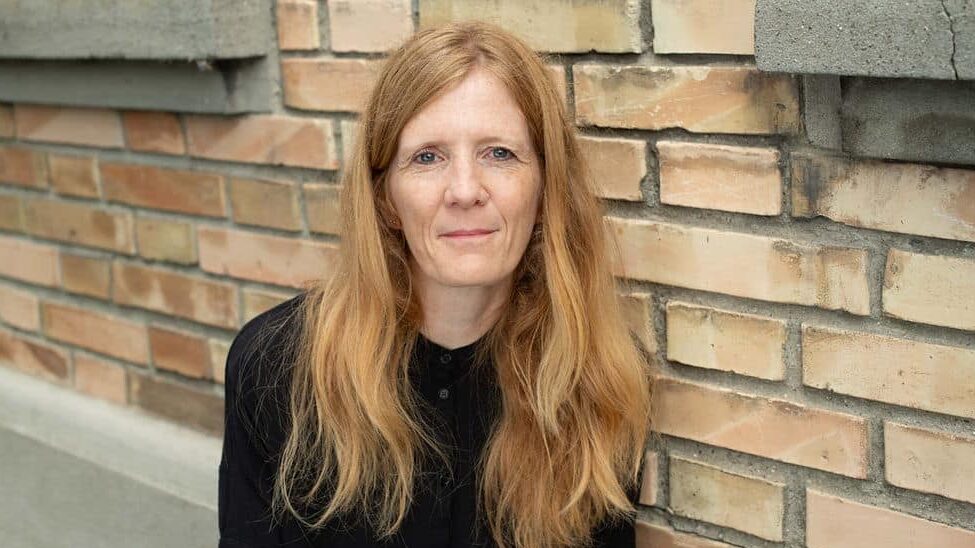 Historikerin Fabienne Amlinger fotografiert vor einer Backsteinmauer.
