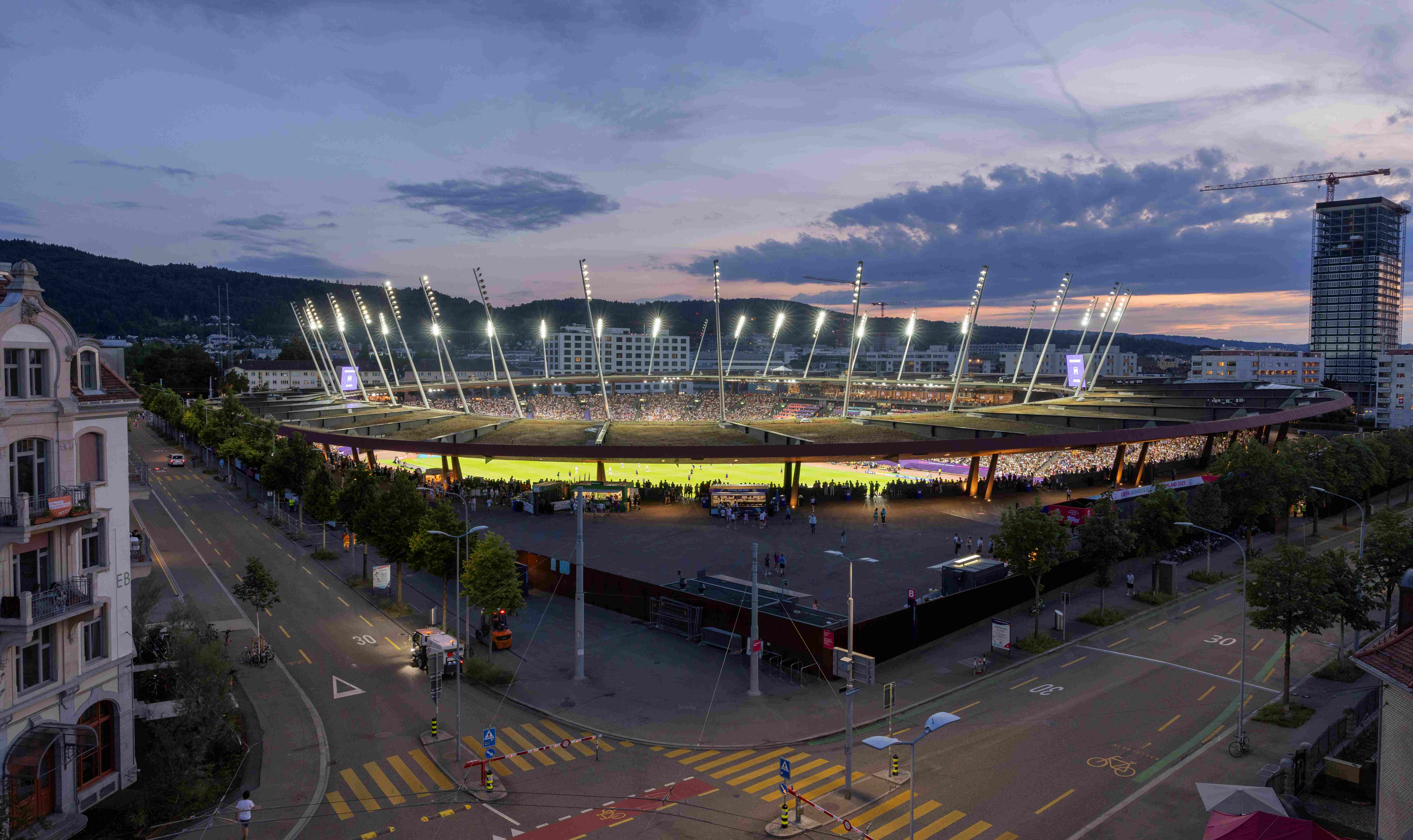 Das Stadion Letzigrund in Zürich hell erleuchtet von den Flutlichtern mit vollen Rängen an einem schönen, lauen Sommerabend.