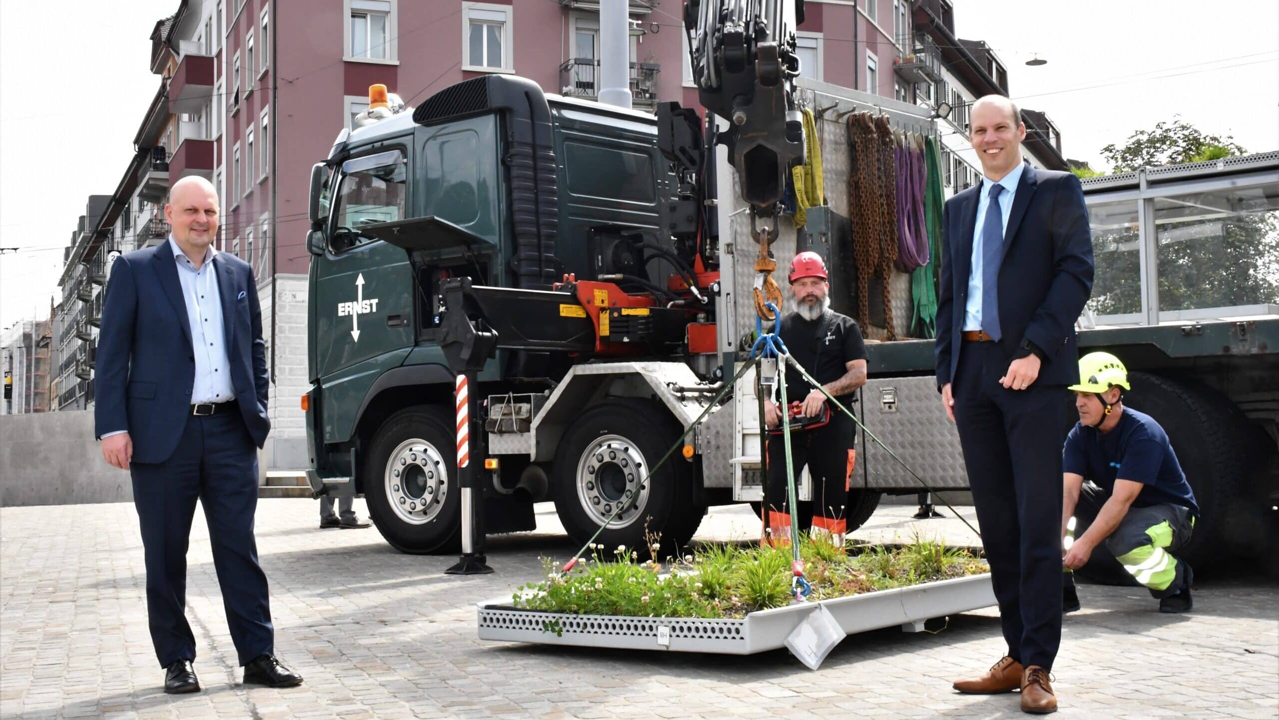 Auf dem Bild sind Stadtrat Michael Baumer (l.) und der damalige VBZ-Direktor Marco Lüthi zu sehen. Im Hintergrund eine der Wannen mit Bepflanzungen, die nachher auf das Dach eines VBZ-Wartehäuschens gehievt wurde.