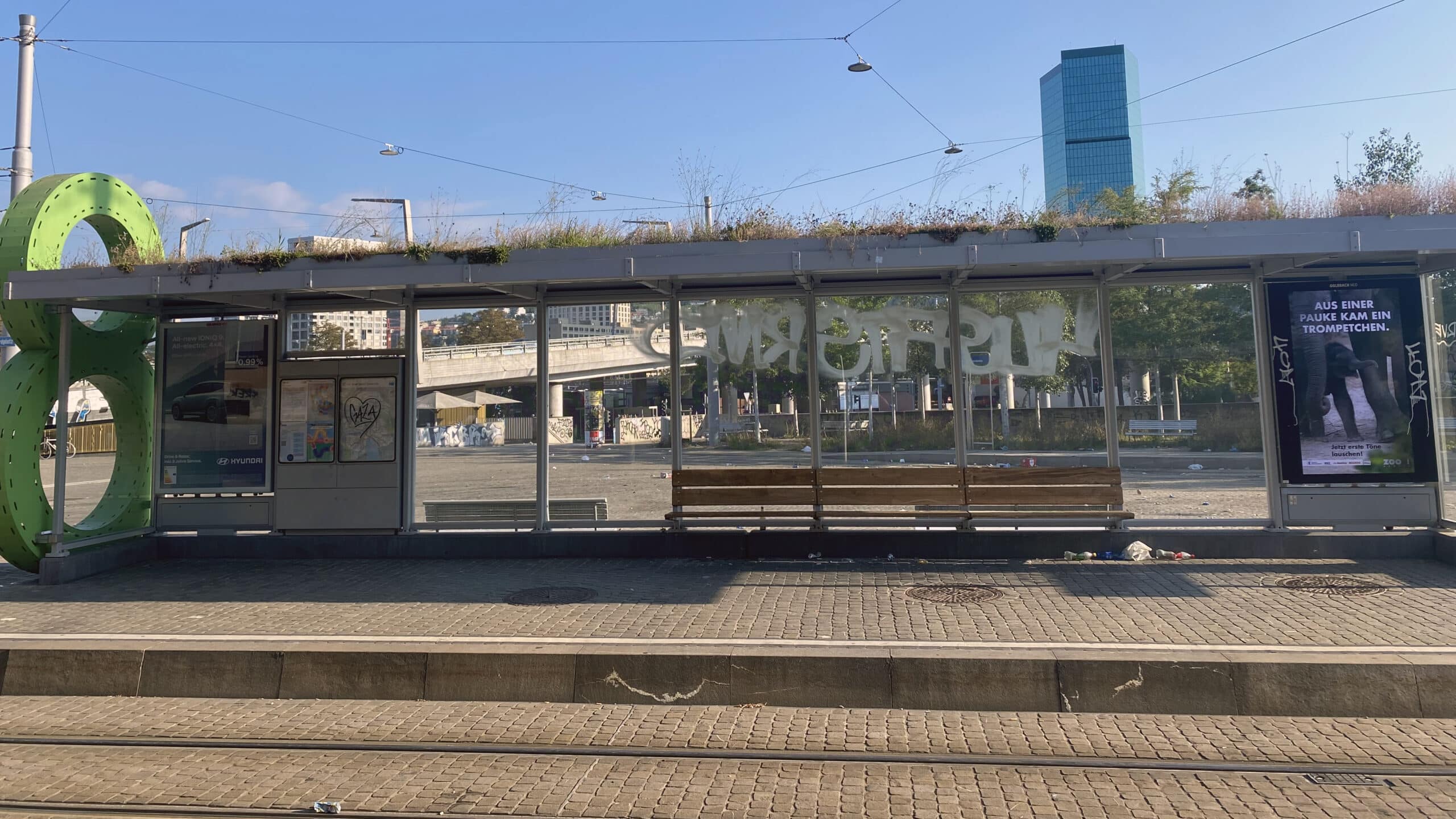 Die Tram-Haltestelle des 8er-Trams am Hardplatz Richtung Hardturm. Das Dach ist begrünt, im Hintergrund ragt der Prime Tower empor.