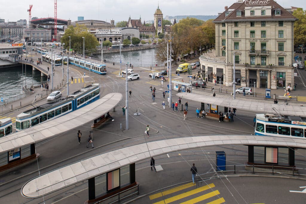 Das Central in Zürich von oben. Man sieht die Haltestellendächer, Passagiere, Trams, Autos, die Limmat.