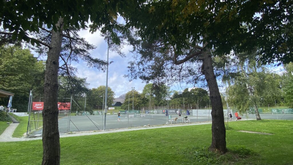 Auf dem Bild zu sehen die Sicht in Richtung heutigem Hallenbad Oerlikon mit den Tennisplätzen im Vordergrund und den vielen Bäumen.