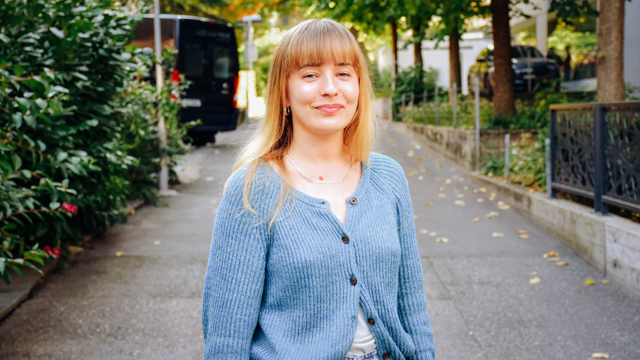 Gianna Berger trägt eine blaue Strickjacke. Sie lächelt in die Kamera.