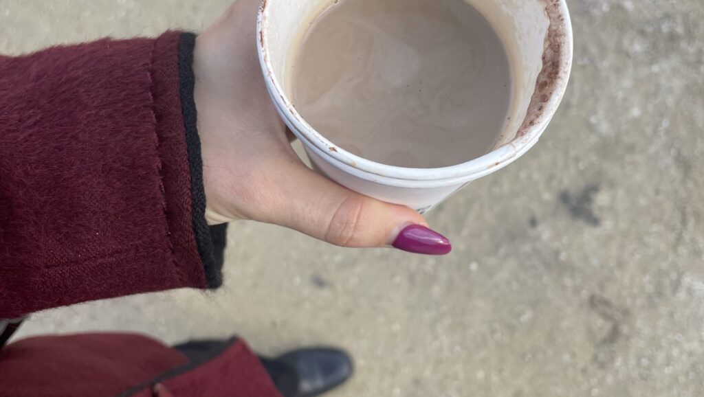 Zu sehen die Hand von Lara Alina Hofer mit einem Becher Kaffee.