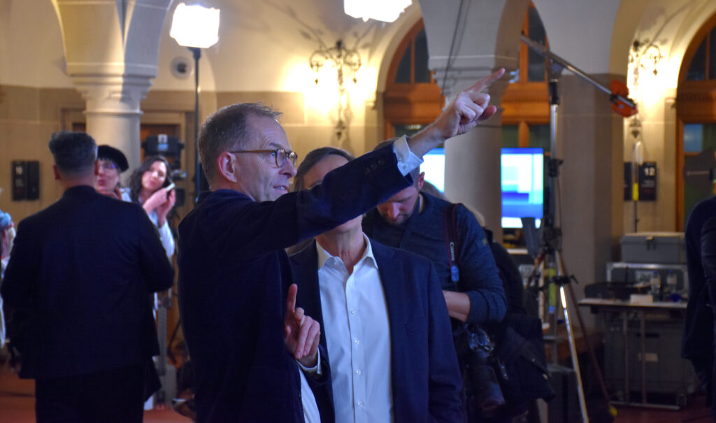 Ein Mann hat seinen Arm ausgestreckt und zeigt mit einem Finger einer anderen Person etwas.