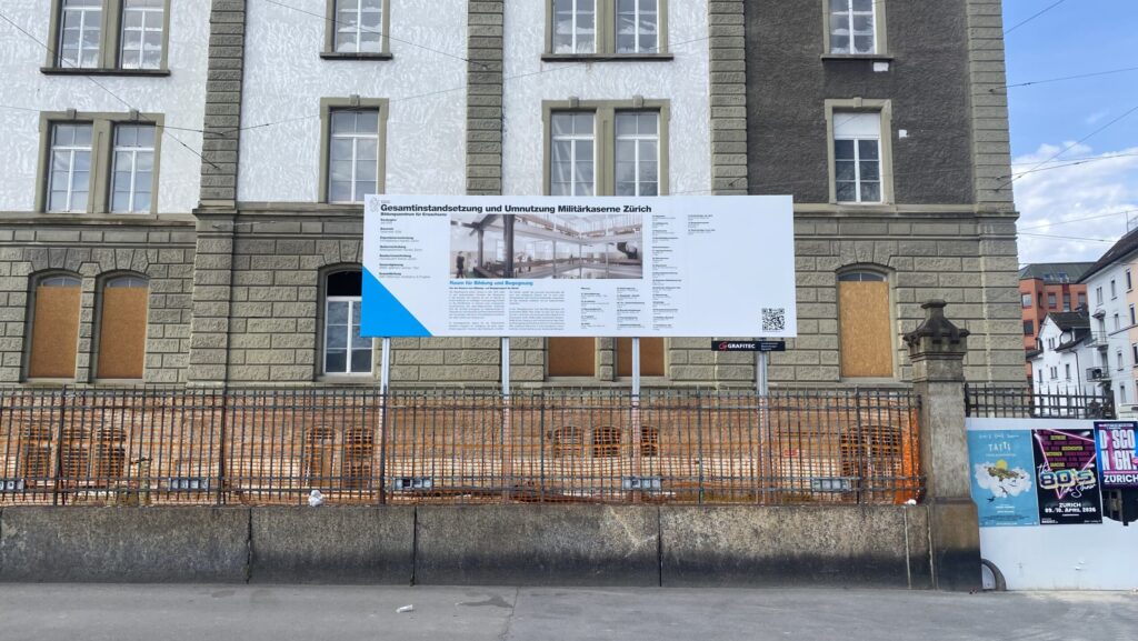 Zu sehen ist ein Teil der eigentlichen Kaserne entlang der Sihl mit der Bautafel, die zeigt, was bis wann saniert wird.