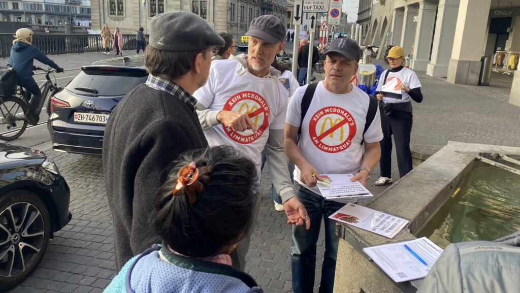 Zu sehen sind Gegner des McDonald's-Projekts, wie sie am Limmatquai Unterschriften sammeln.