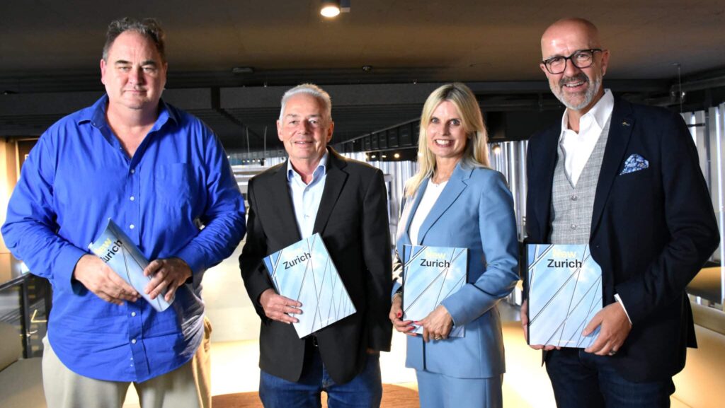 Vier Personen stehen mit Broschüren in der Hand in einem modernen Innenraum.
