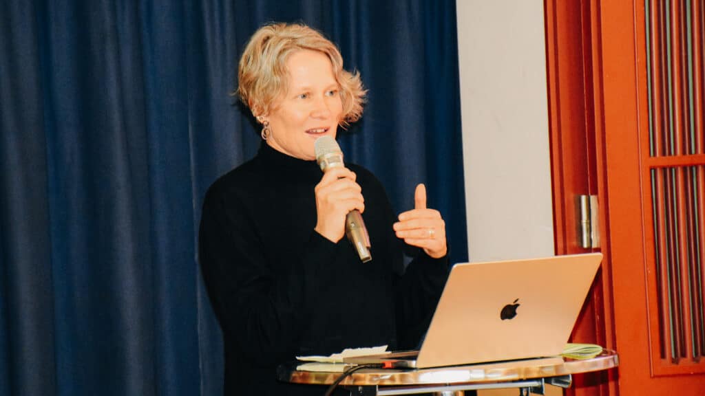 Tanja Maag spricht mit einem Mikrofon neben einem geöffneten Laptop.