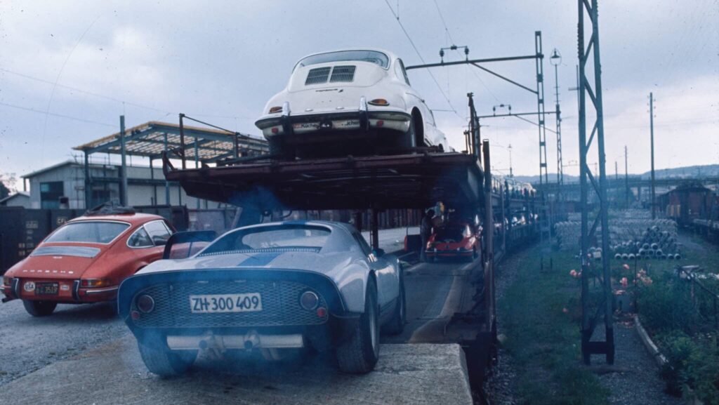 Zu sehen ist der Autoverlad in den 1980er Jahren in Zürich-Altstetten. Es waren doppelstöckige Autozüge, auf dem Bild zu sehen drei Sportwagen, die eben auf einen Eisenbahnwagen fahren. 