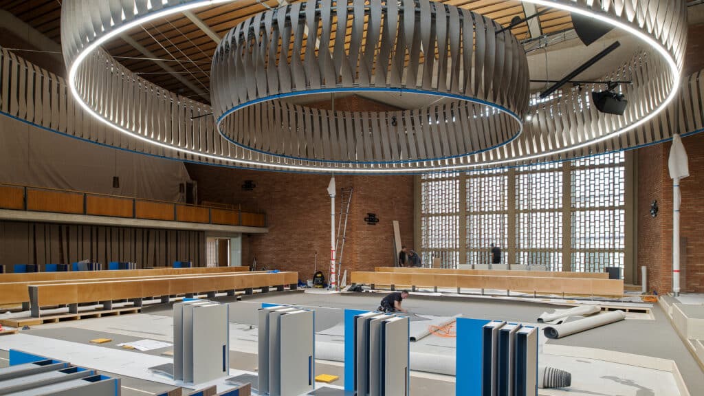 Ratssaal im Rathaus Hard während des Umbaus mit grossen Leuchtringen an der Decke und Arbeitsmaterial am Boden.