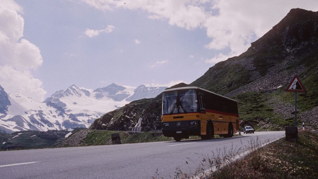 Ein Mercedes-Postauto im Jahr 2001, wie es über den Berninapass fährt. im Hintergrund Schneeberge wie der Piz Cambrena.