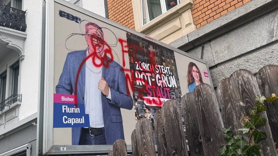 Beschmierte Wahlplakate in Zürich; auf einem Plakat ist ein Kandidat zu sehen, dessen Gesicht mit roter Farbe übersprüht wurde.