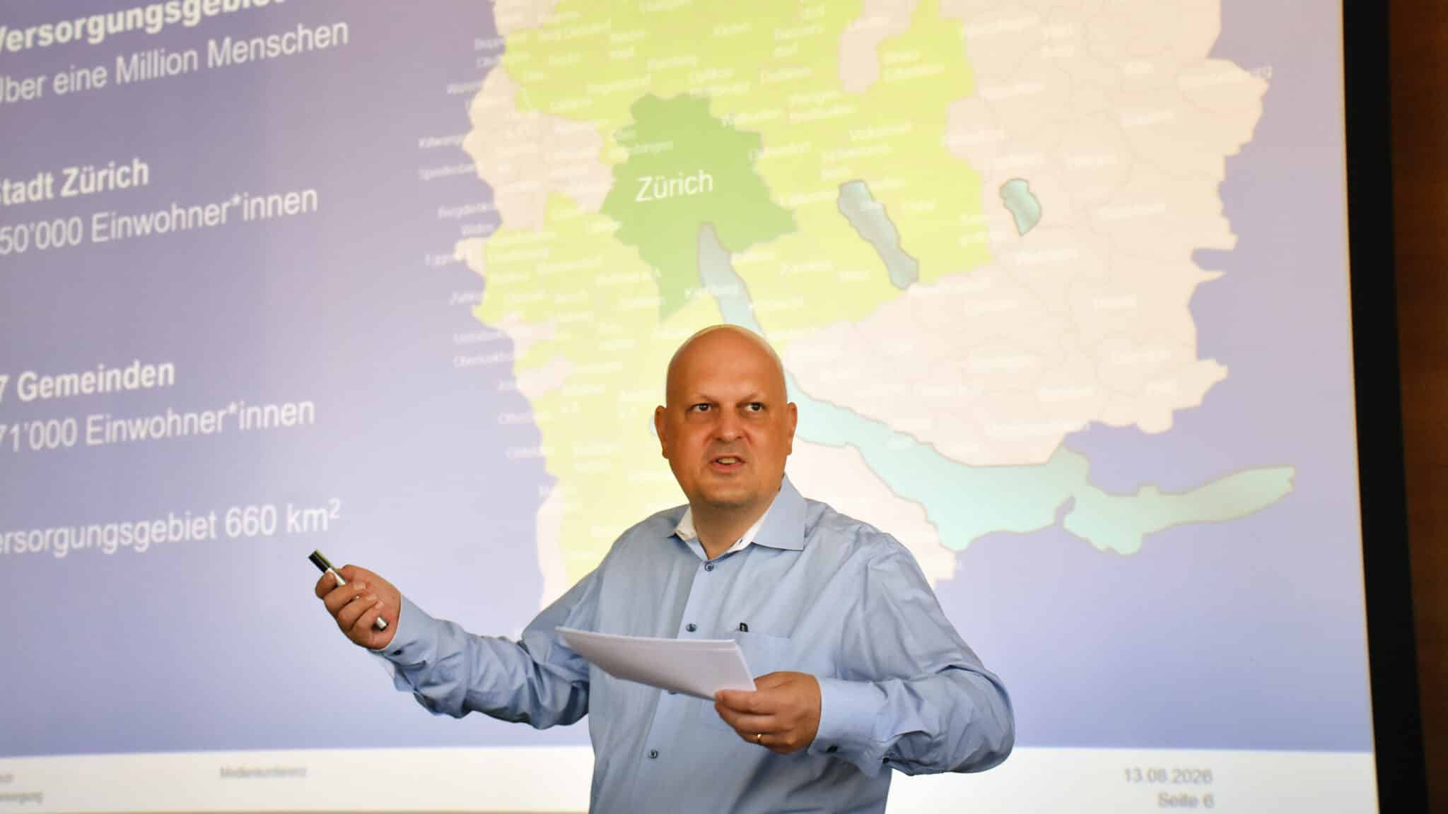Mann hält eine Präsentation vor einer Karte des Versorgungsgebiets der Wasserversorgung.