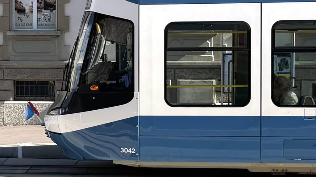 Nahaufnahme eines blau-weissen Cobra-Trams mit kleinen Fahnen an der Front.