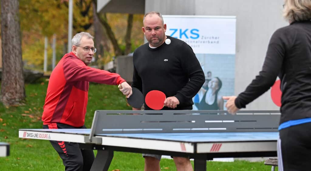 Männer spielen draussen Tischtennis.