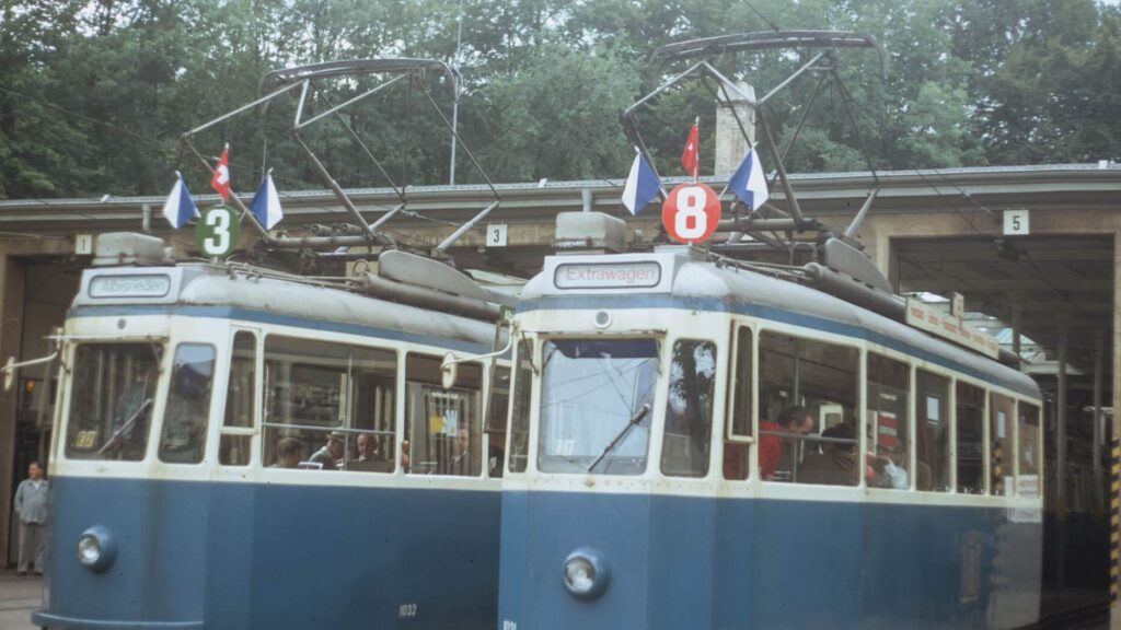 zu seheh sind zwei ältere Trams mit der Beflaggung oben auf dem Dach. Die Aufnahme stammt vom Tramdepot Burgwies. Die Trams stehen vor dem Depot.