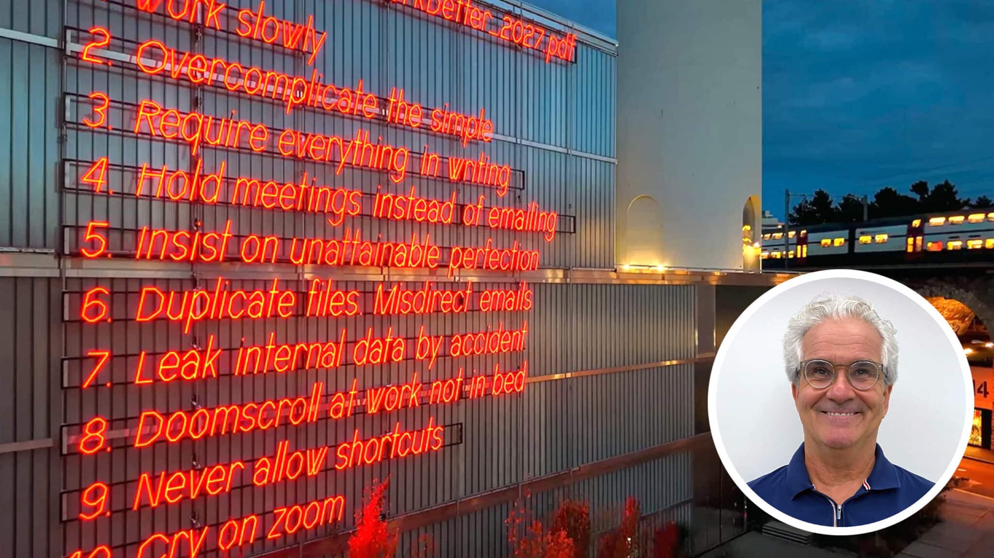 Rote Neoninstallation mit englischen Büroregeln an einer Gebäudefassade bei Nacht. Rechts unten ist ein rundes Porträt eines lächelnden Mannes eingeblendet.