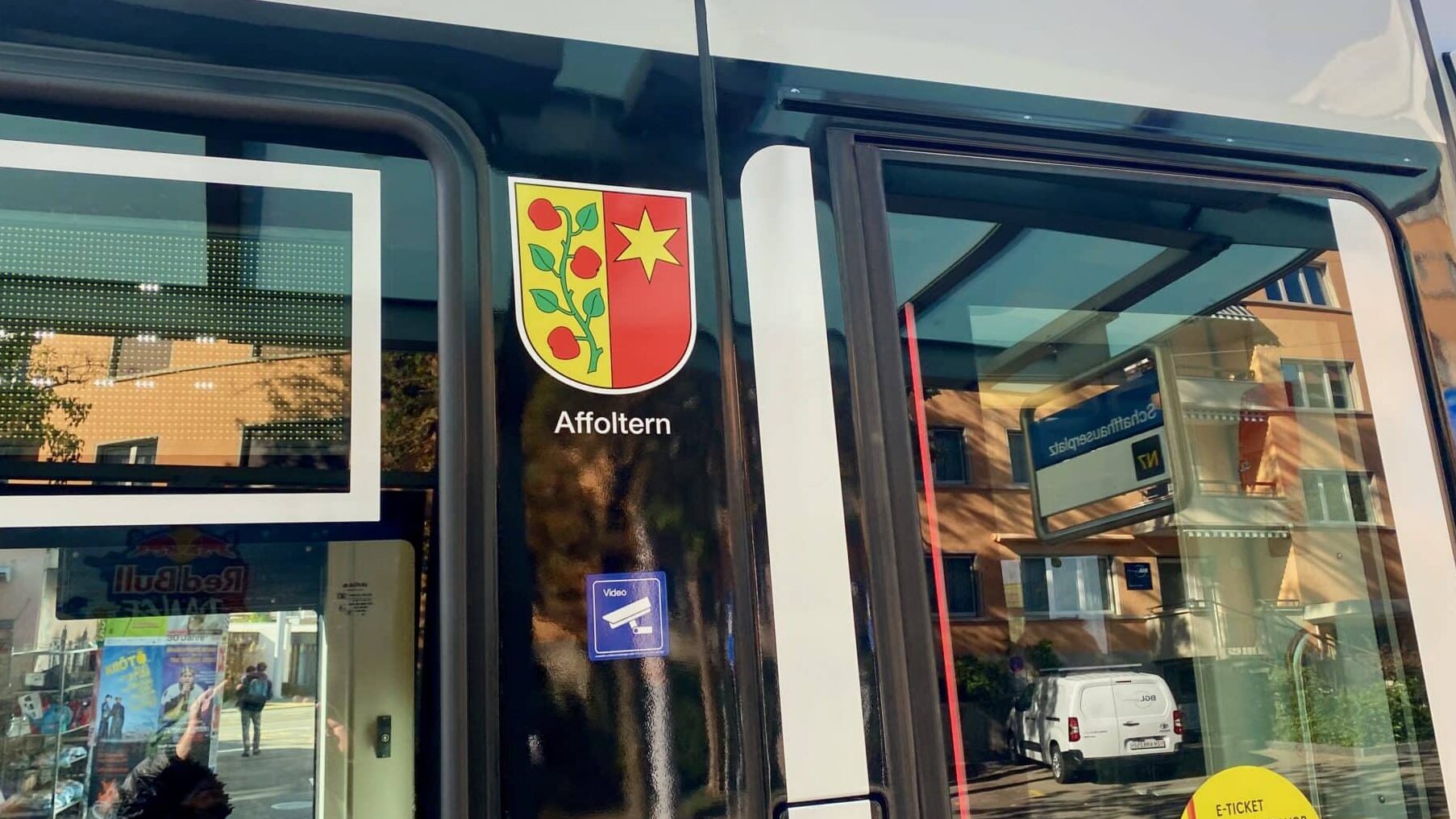 ein Tram von aussen mit dem Wappen des Quartiers Affoltern in Zürich. Es ist zweigeteilt, gelb/rot mit einem Apfelzweig und einem Stern.